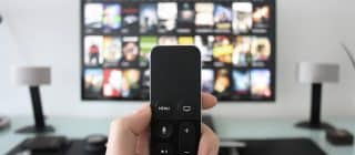 remote control held up in front of a TV screen with netflix displayed