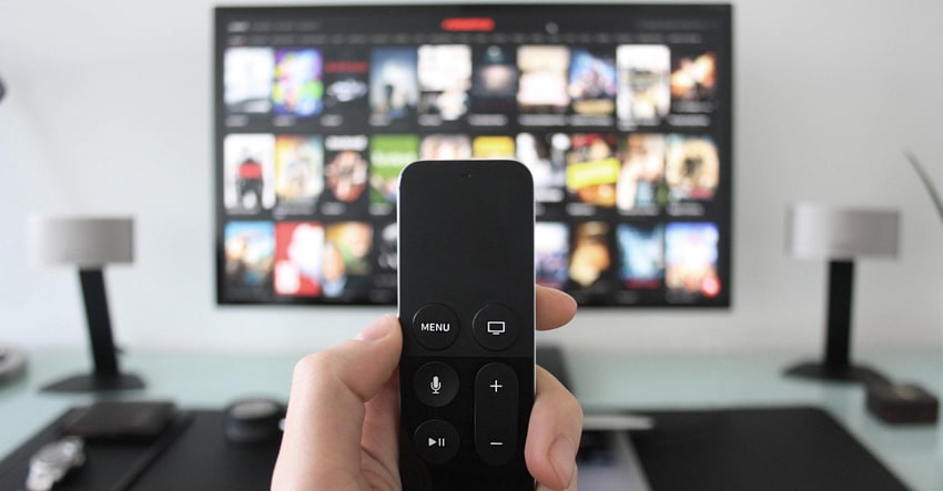 remote control held up in front of a TV screen with netflix displayed