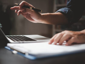 man working on laptop with paper and pen