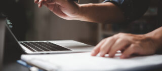 man working on laptop with paper and pen
