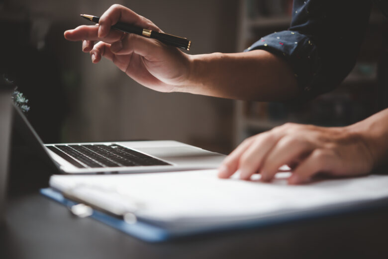 man working on laptop with paper and pen