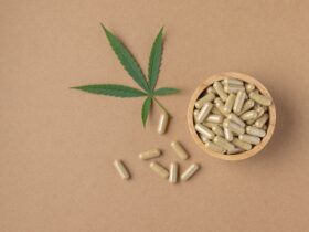 cbd pills on brown background with cannabis leaf