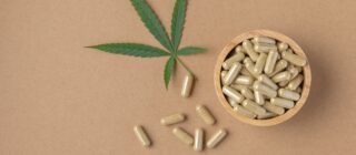 cbd pills on brown background with cannabis leaf