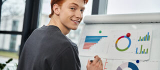 Young redheaded man looking at graphs and charts