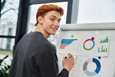 Young redheaded man looking at graphs and charts