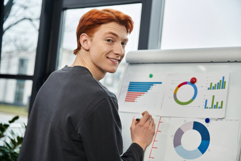 Young redheaded man looking at graphs and charts