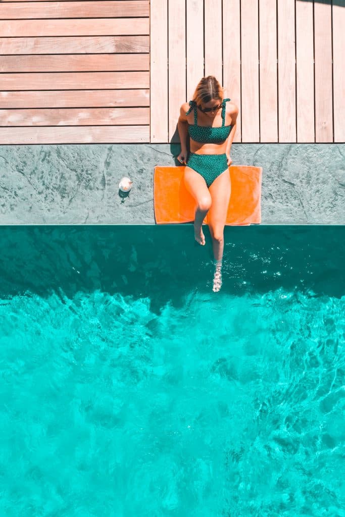 a woman in a bathing suit sitting on the edge of a swimming pool