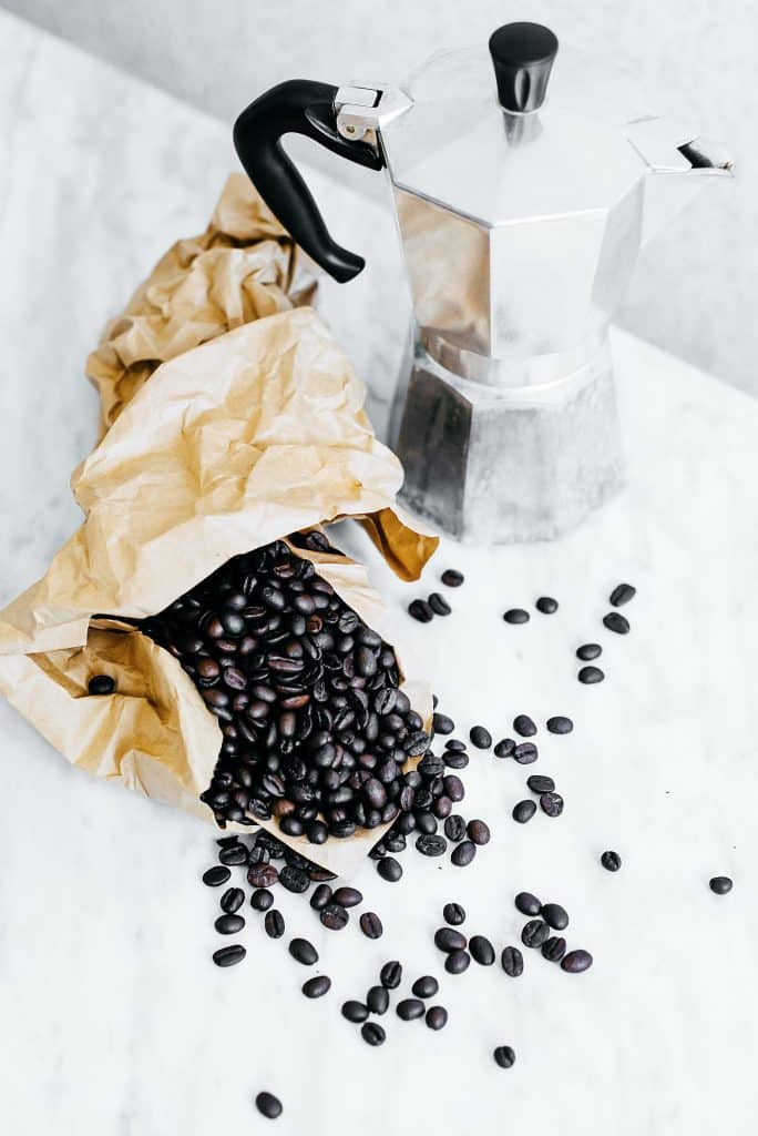 bag of coffee beans on a counter next to a metal coffee pitcher