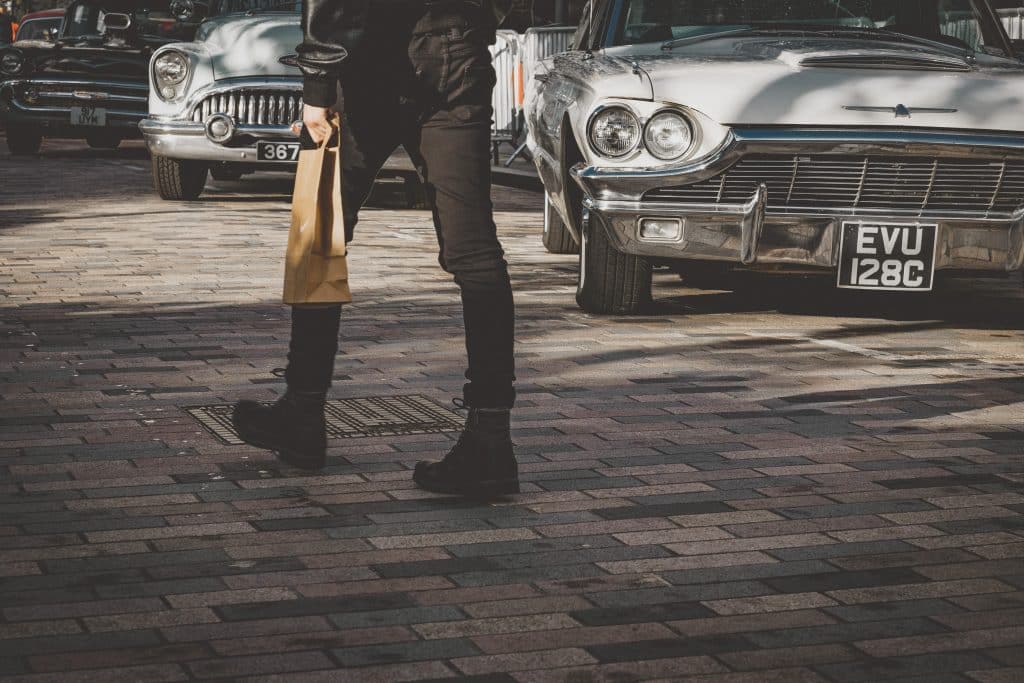 man walking down the street with a brown paper bag