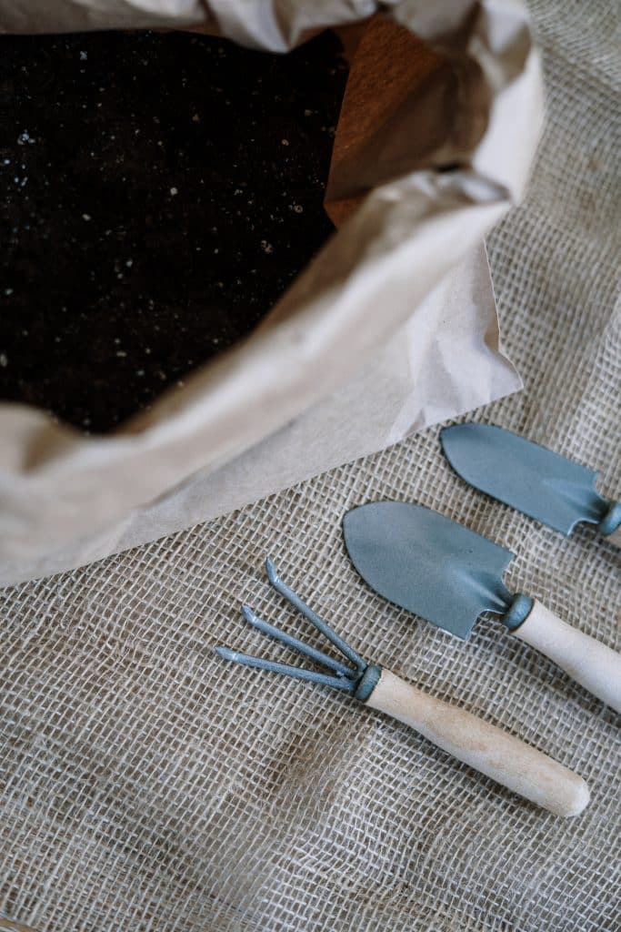 a bag of potting soil next to gardening tools