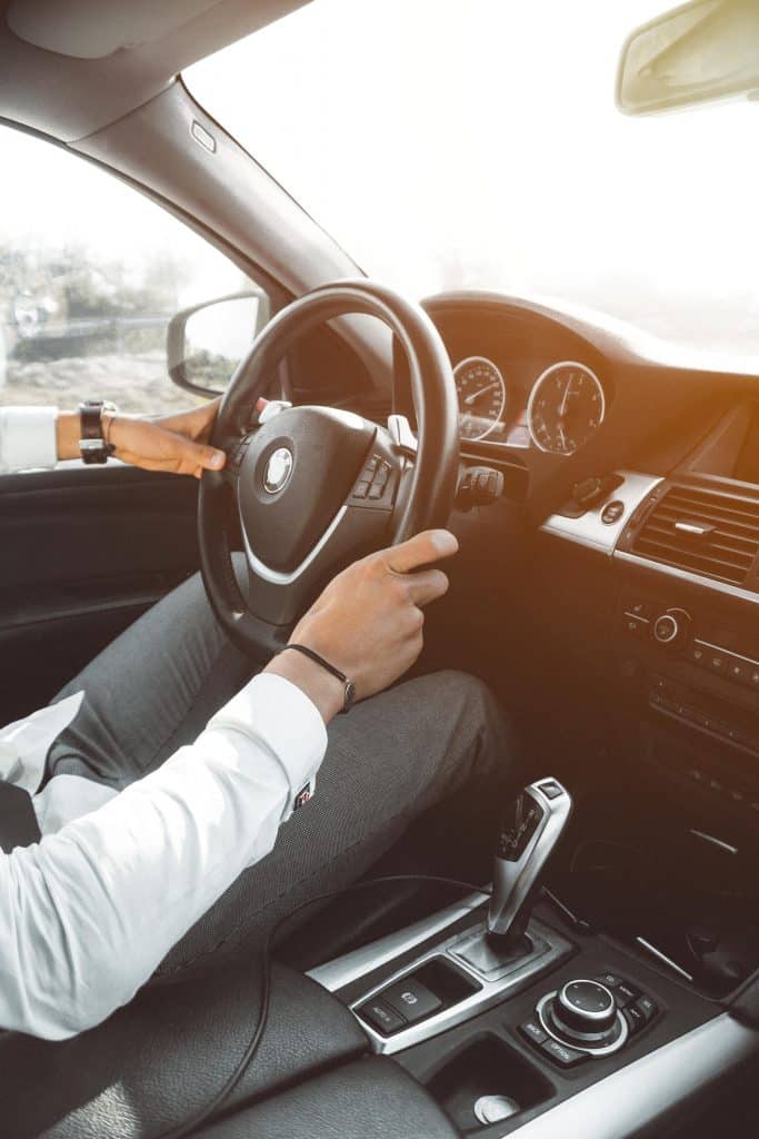 a man driving a BMW car. The shot is the interior while he sits at the wheel.