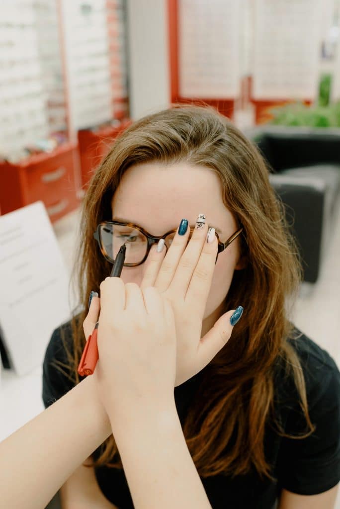 a woman getting her eyeglasses measured against her eye