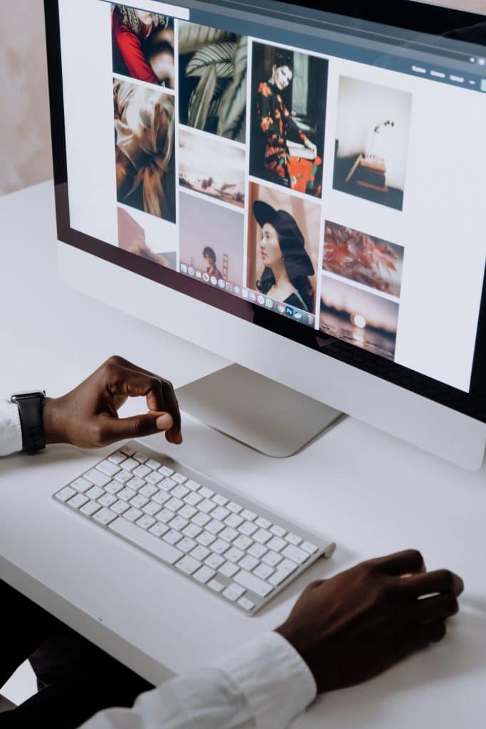 man's hands near a keyboard while he browses images on his monitor.