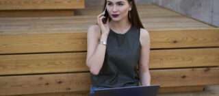 Caucasian woman making business call with laptop and phone