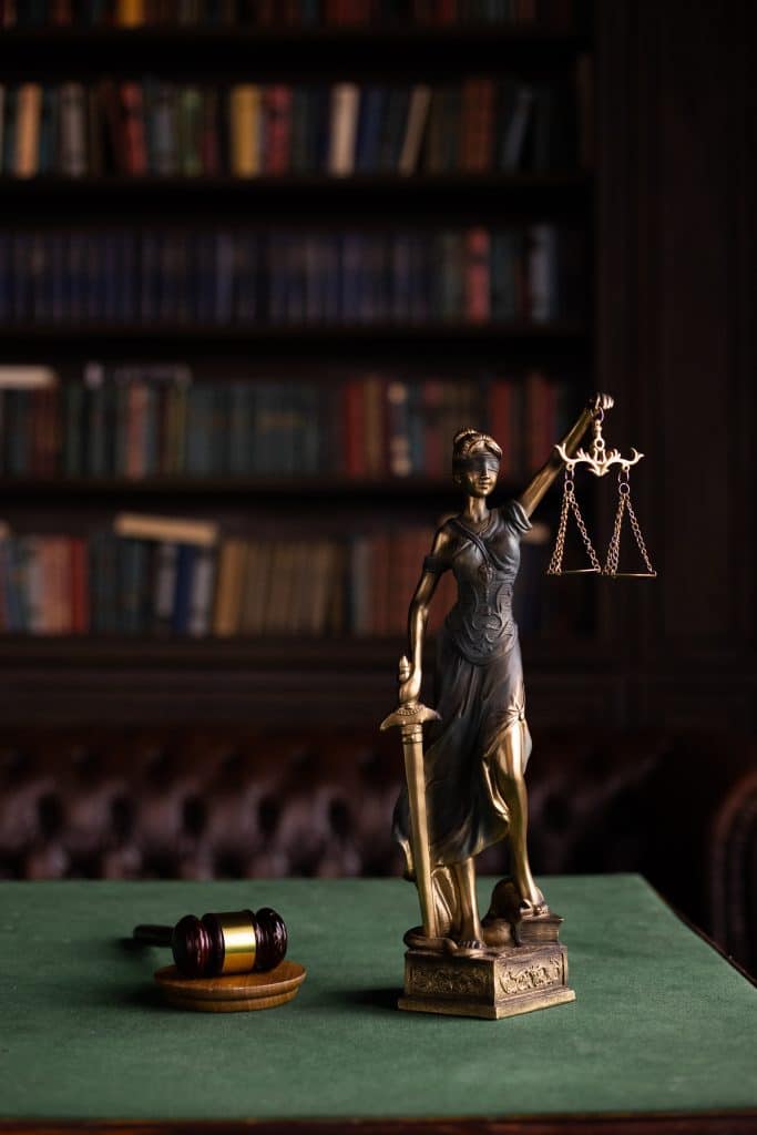 small statue of lady justice sitting on a desk next to a gavel