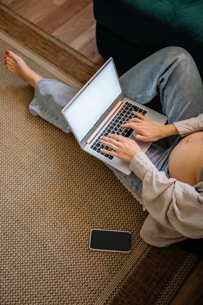 pregnant woman sitting on the floor with a laptop on her lap