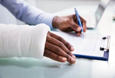 man with an arm in a cast signing a document