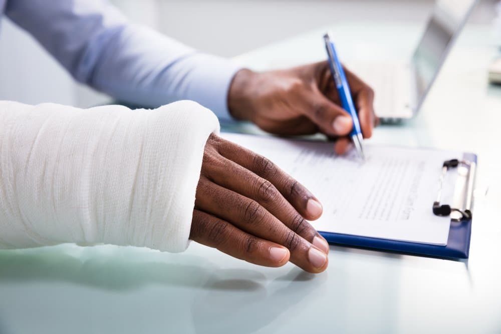 man with a hand injury signing a form