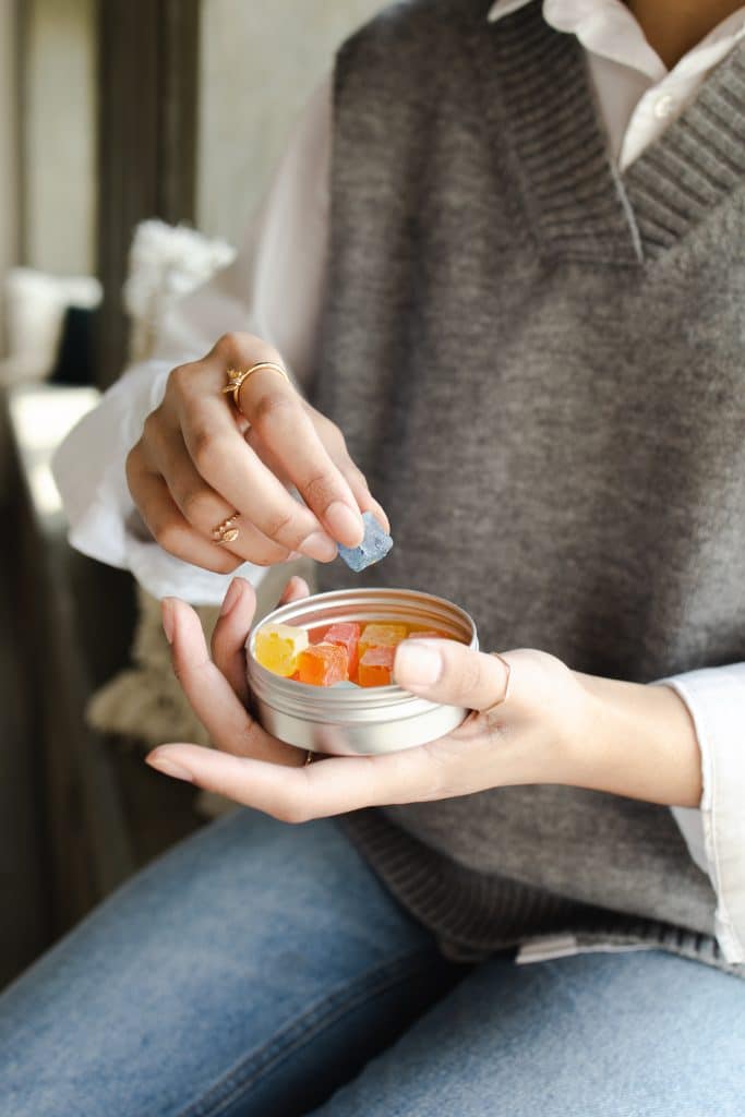 a woman taking a CBD gummy out of a container