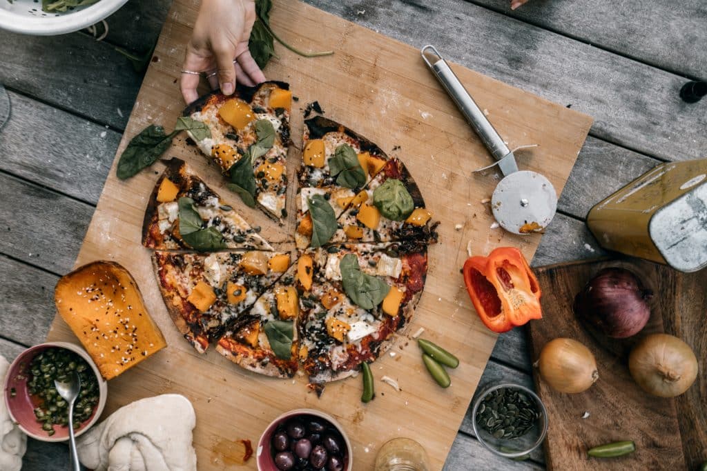 a vegetarian pizza on a cutting board with ingredients around it