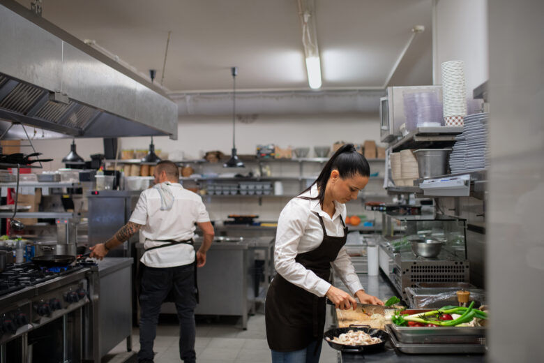 female chef cutting vegetables in kitchen