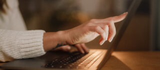 woman's hands typing on laptop