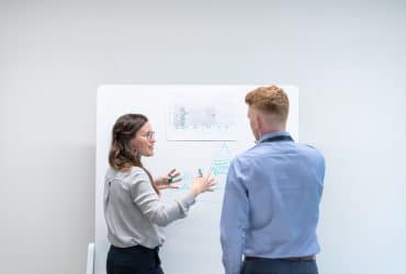 engineering manager discussing notes on board with an engineer