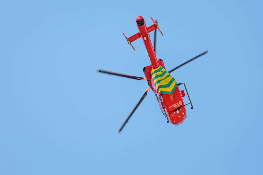 bottom view of a red and yellow medical emergency helicopter