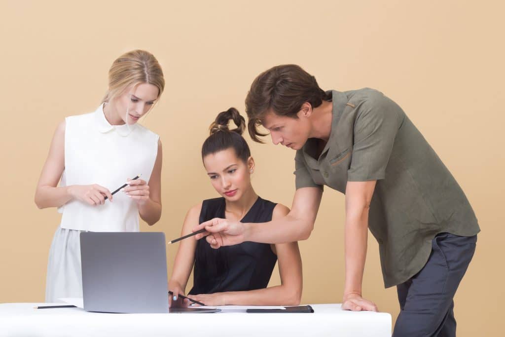 two women and a man working together over a laptop
