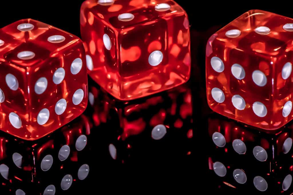 3 red dice sitting on a reflective surface