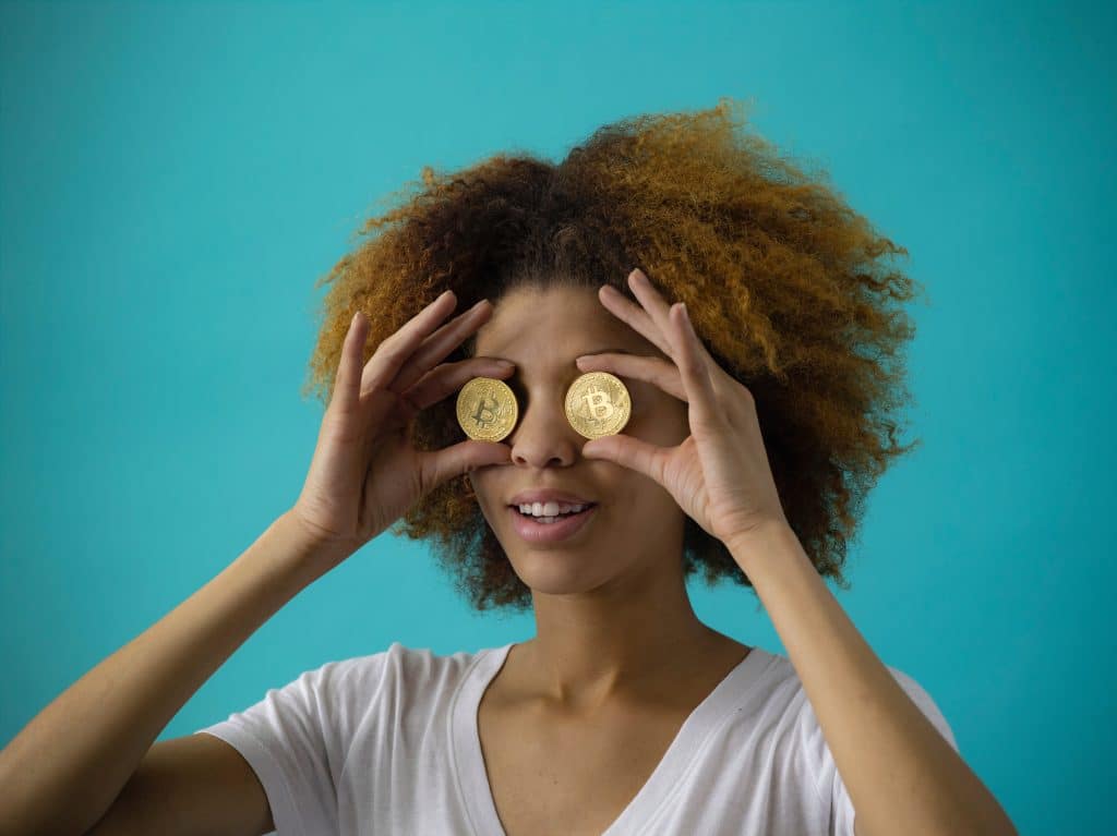 woman holding bitcoins up to her eyes