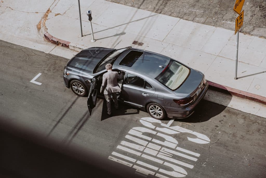 overhead view of a man climbing into a car parked on the street.