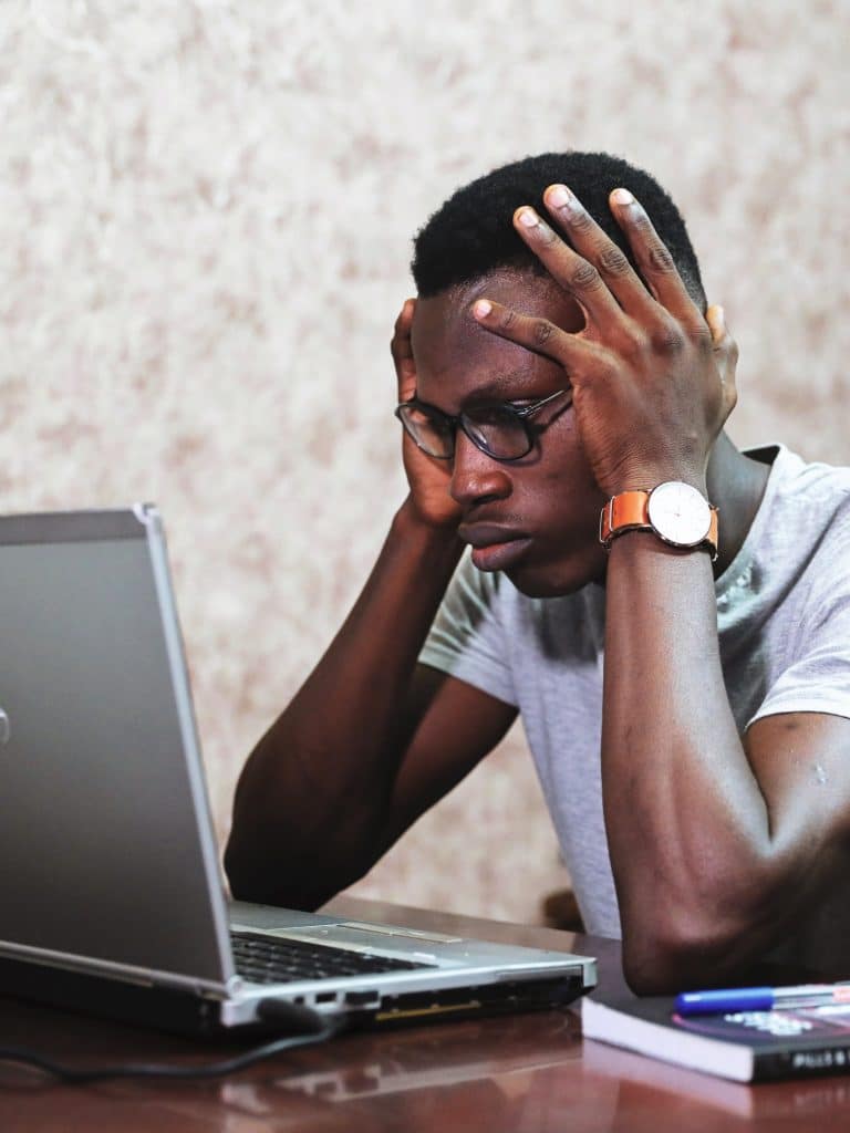 man sitting at his laptop looking frustrated