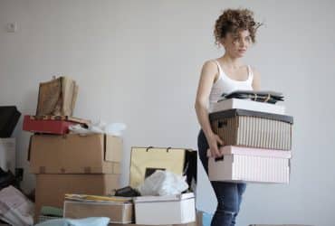 concentrated woman carrying stack of cardboard boxes for relocation