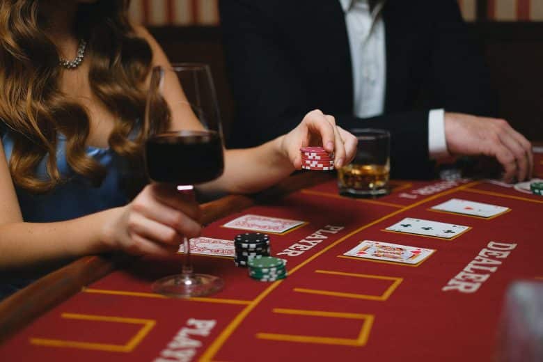 elegant man and woman playing poker in a casino and drinking wine