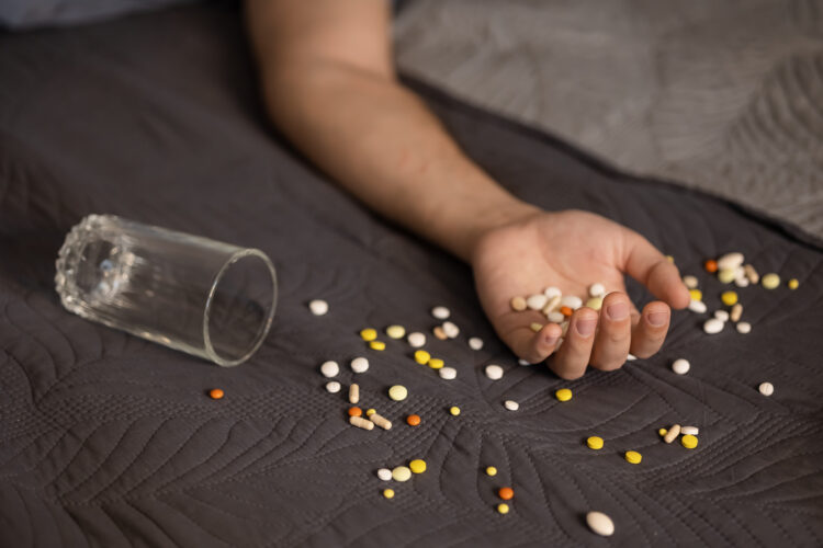male hand with pills and water overdose