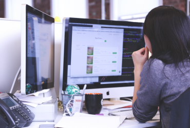 many businesses need advanced software such as what this woman is using at her desk with two monitors