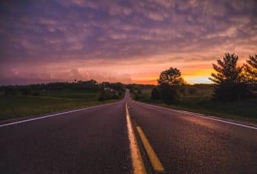 photo of empty road in between grass field during golden hour