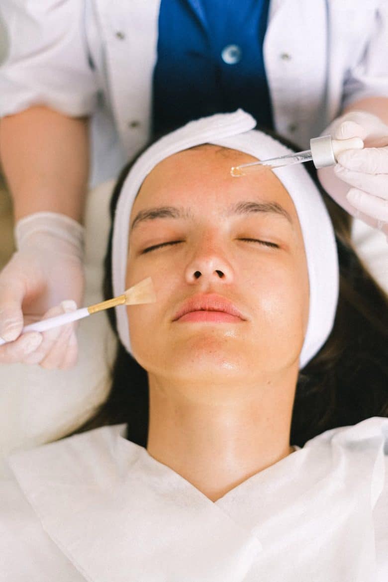 beautician putting cosmetic product on female client face