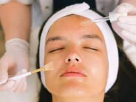 beautician putting cosmetic product on female client face