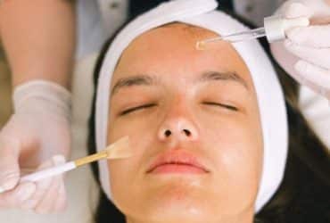 beautician putting cosmetic product on female client face