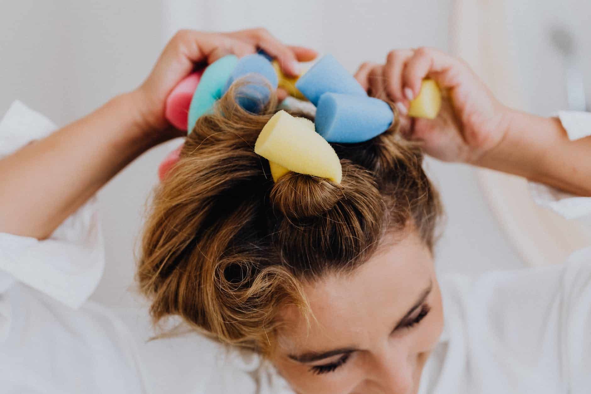 woman fixing her hair using hair rods curlers - hairstyling tips
