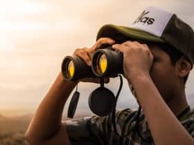 man looking in binoculars during sunset