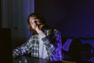 man eating pizza while on computer in dark room