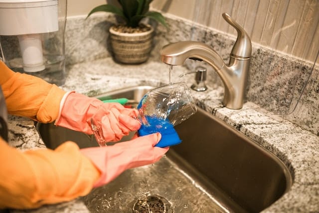 person washing glass in sink