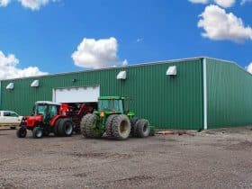 Large steel farm building with tractors parked in front