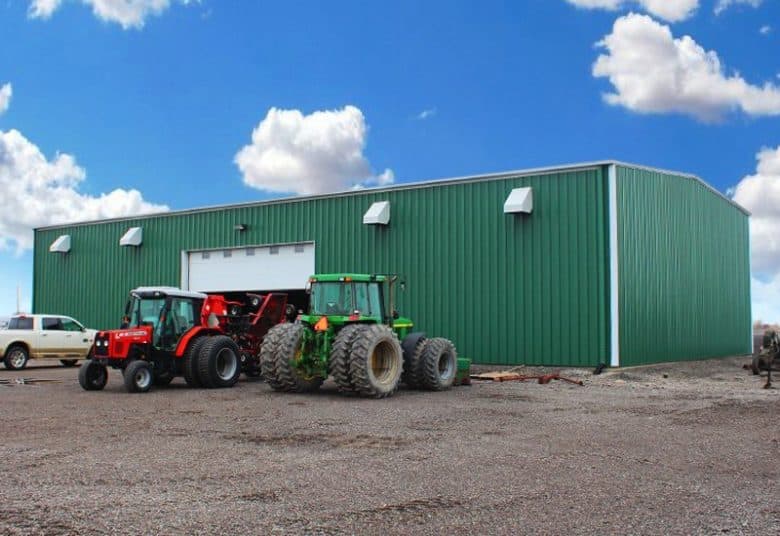 Large steel farm building with tractors parked in front
