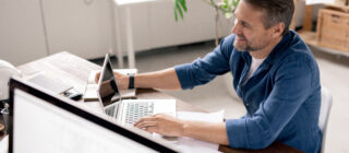 happy. smiling man looking at laptop at desk in home office