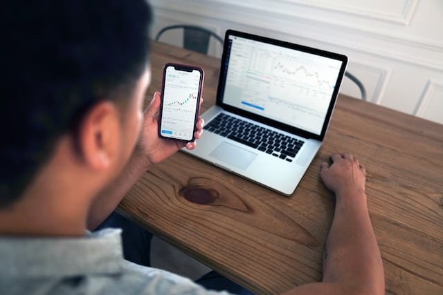 millennial looking at investments on laptop and phone