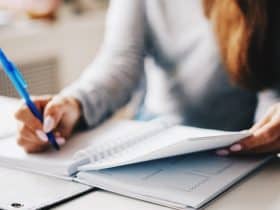 woman at desk writing in notebook